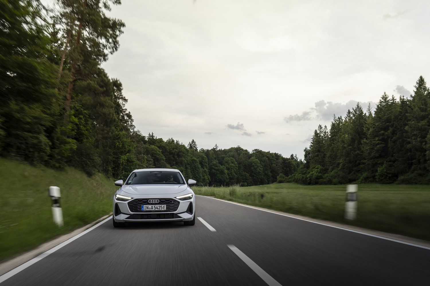 2026 Audi A5 e-hybrid quattro driving towards camera on a forest road, straight-on front