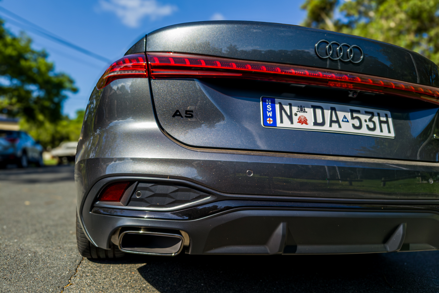 Close-up of 2026 Audi A5 Sedan e-hybrid quattro rear A5 badge and exhaust tip
