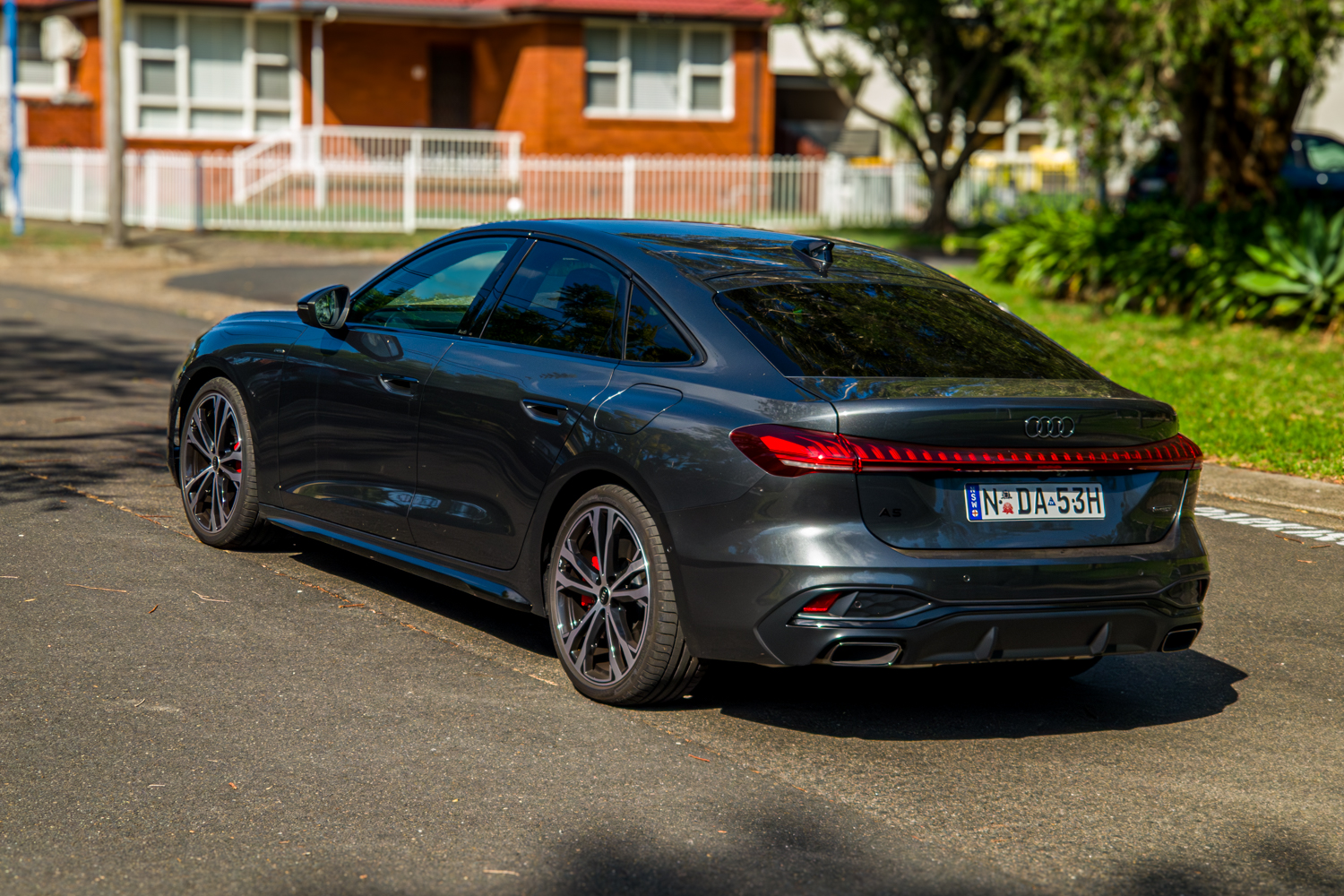 Right-rear three-quarter of the 2026 Audi A5 Sedan e-hybrid quattro in a suburban setting