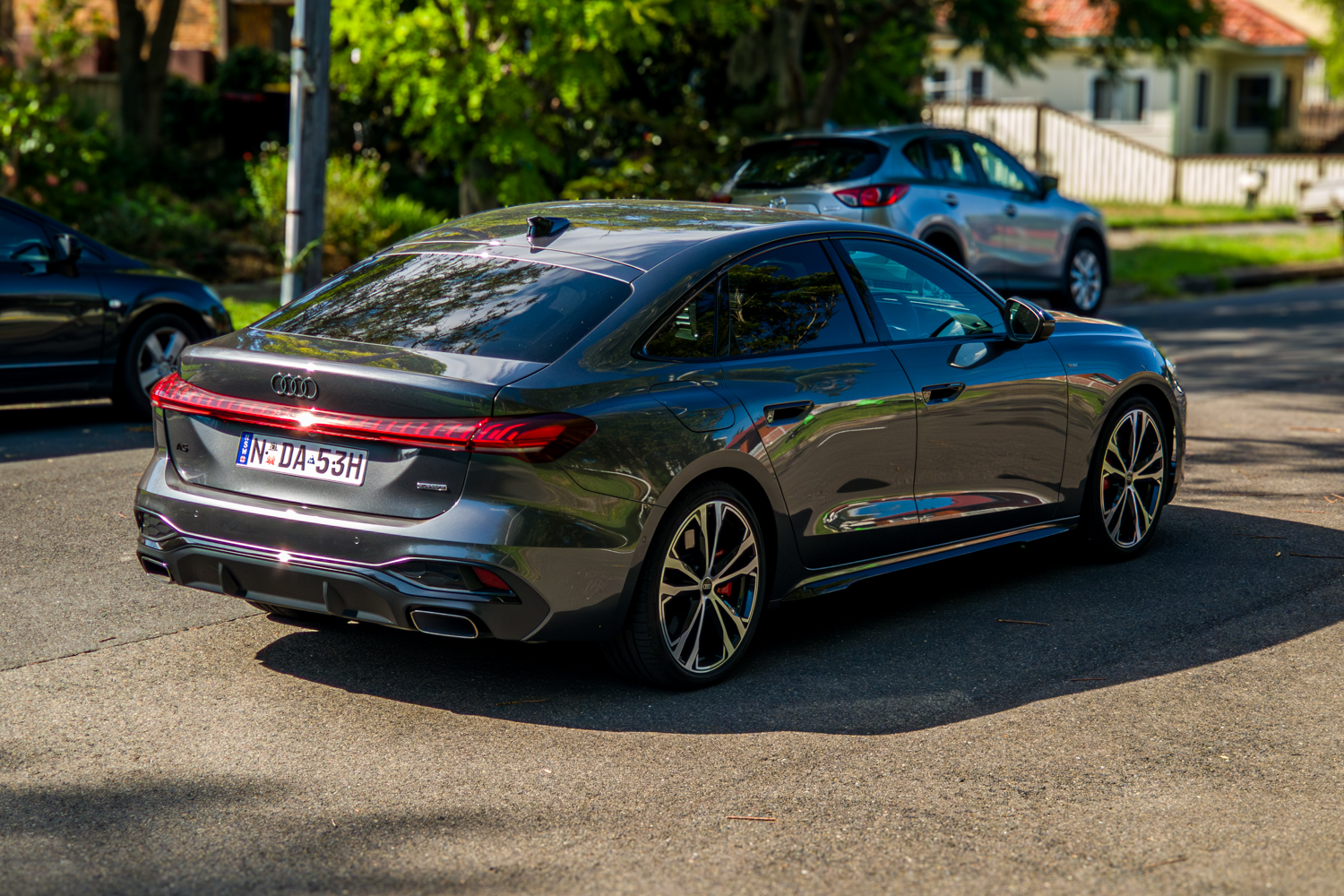 Rear three-quarter of the 2026 Audi A5 Sedan e-hybrid quattro showing LED tail lights and exhausts