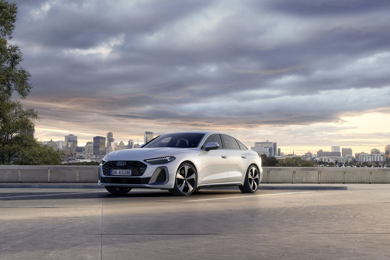 White 2026 Audi A5 Sedan e-hybrid quattro front three-quarter on a rooftop with a city skyline at dusk