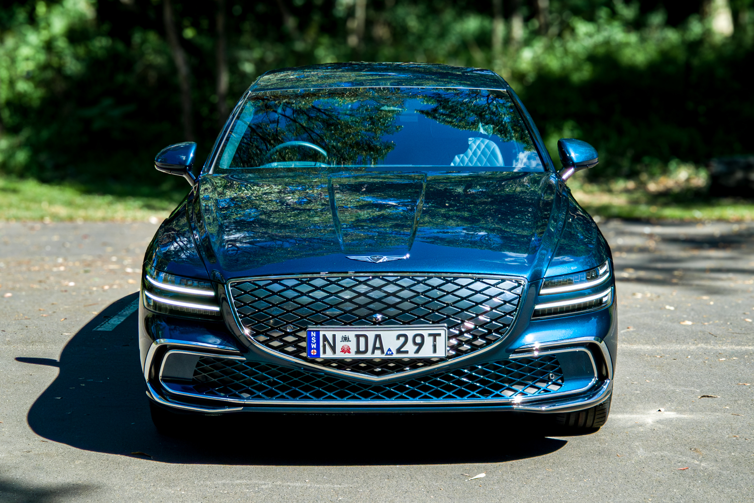2026 Genesis G80 Electrified Matira Blue front view from slightly elevated angle showing full grille