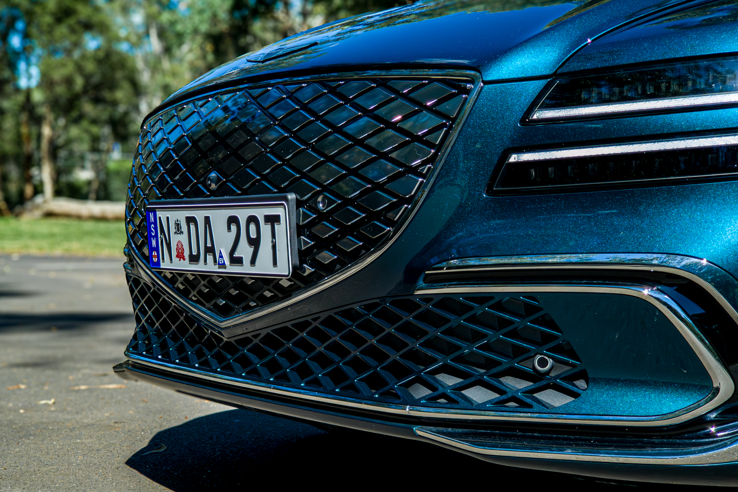 2026 Genesis G80 Electrified Matira Blue crest grille close-up showing diamond mesh pattern and chrome surround