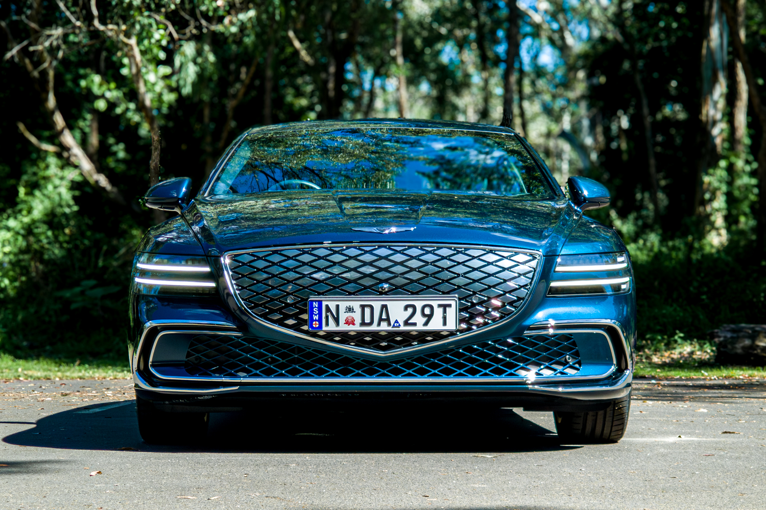 2026 Genesis G80 Electrified Matira Blue straight-on front view showing full grille and DRL headlights