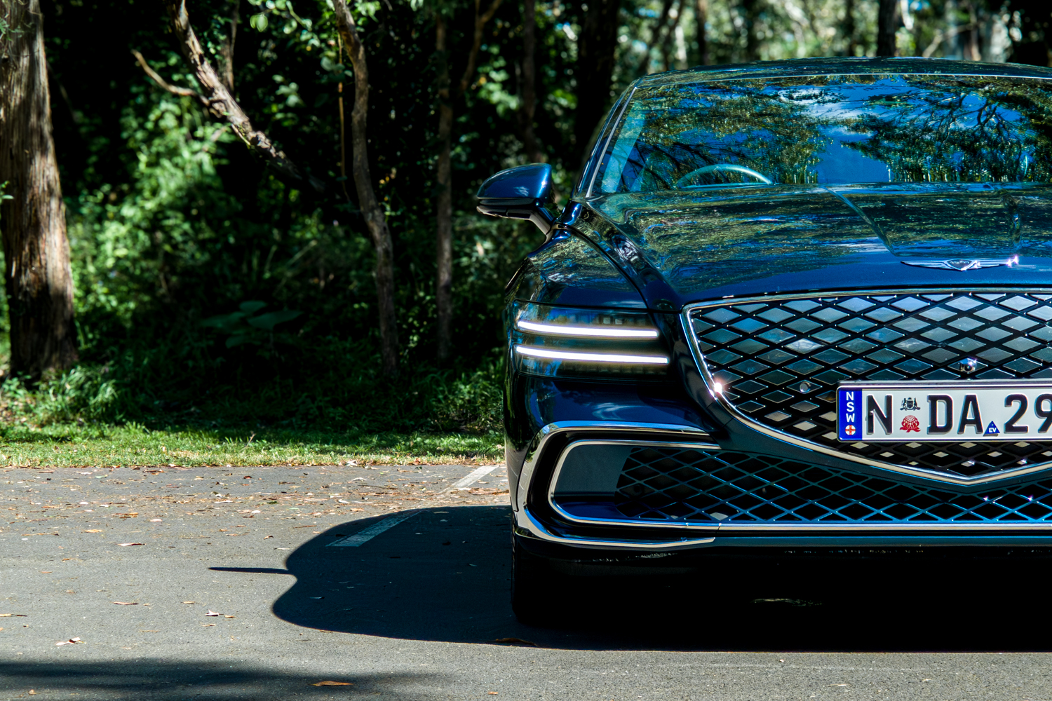 2026 Genesis G80 Electrified Matira Blue front view from near ground level showing DRL headlights