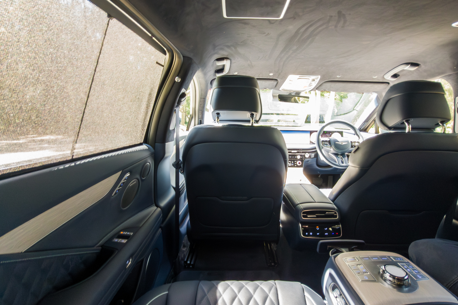 2026 Genesis G80 Electrified rear cabin interior looking forward showing privacy window blinds and rear console
