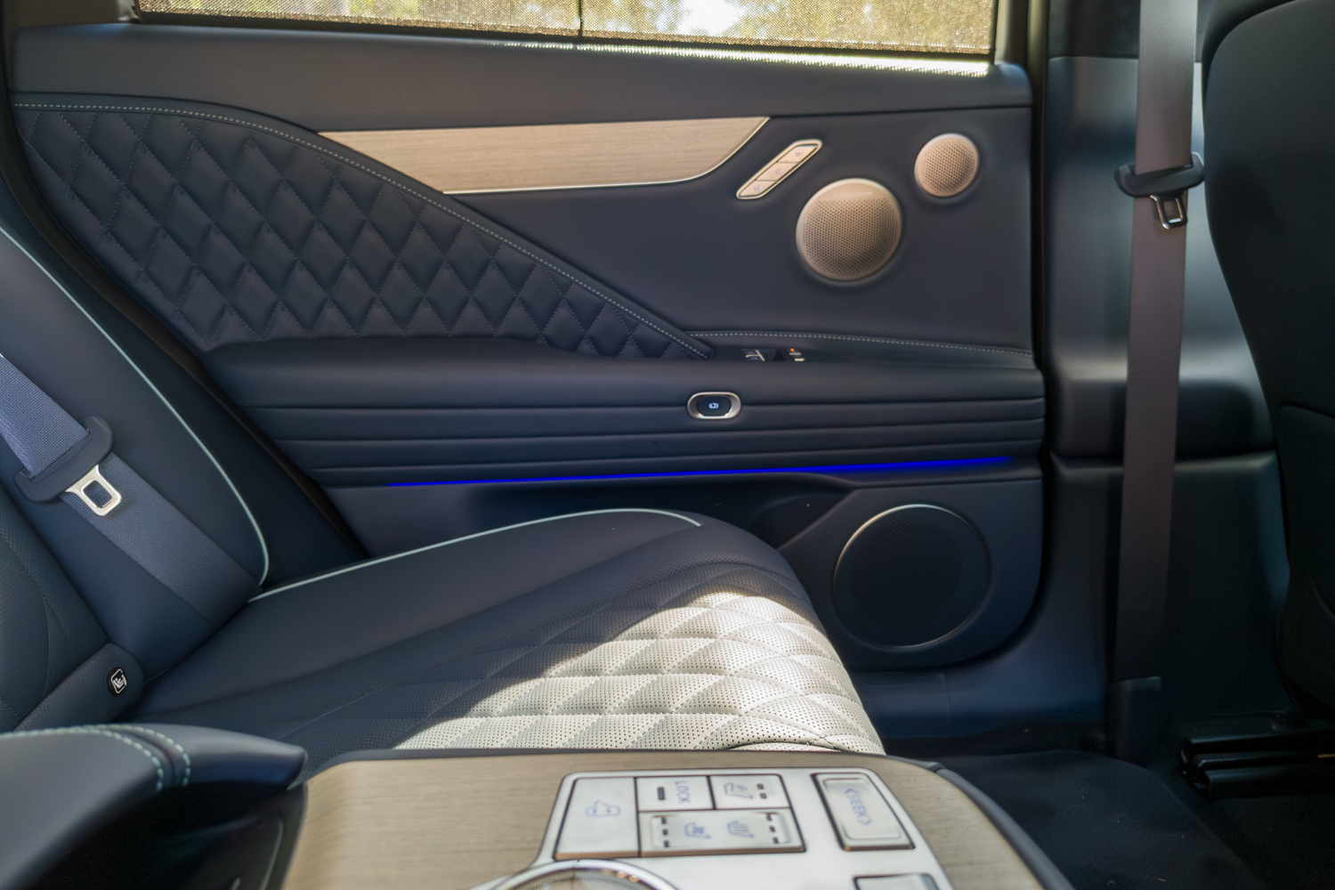 2026 Genesis G80 Electrified interior rear door panel with blue ambient light and Bang and Olufsen speakers