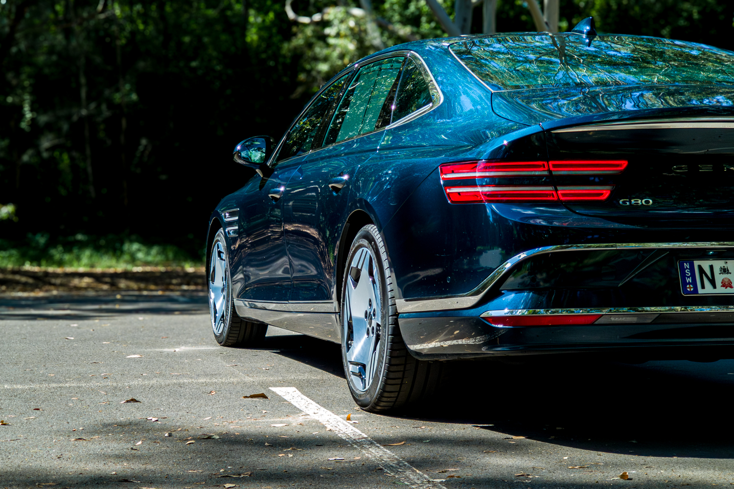 2026 Genesis G80 Electrified Matira Blue rear three quarter driver side close-up showing tail lights and alloy wheel