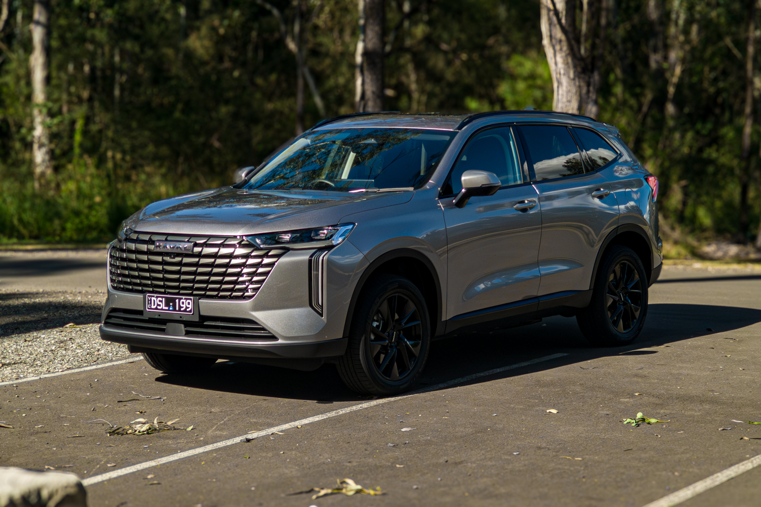 Front exterior of the grey 2026 GWM Haval H6 PHEV parked among gum trees