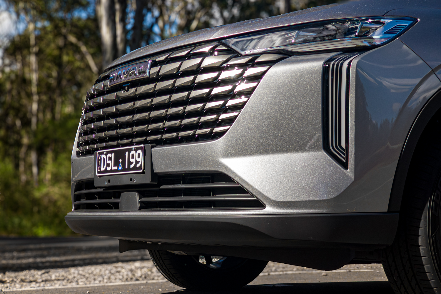 Close up of the 2026 GWM Haval H6 PHEV gloss black grille and headlight