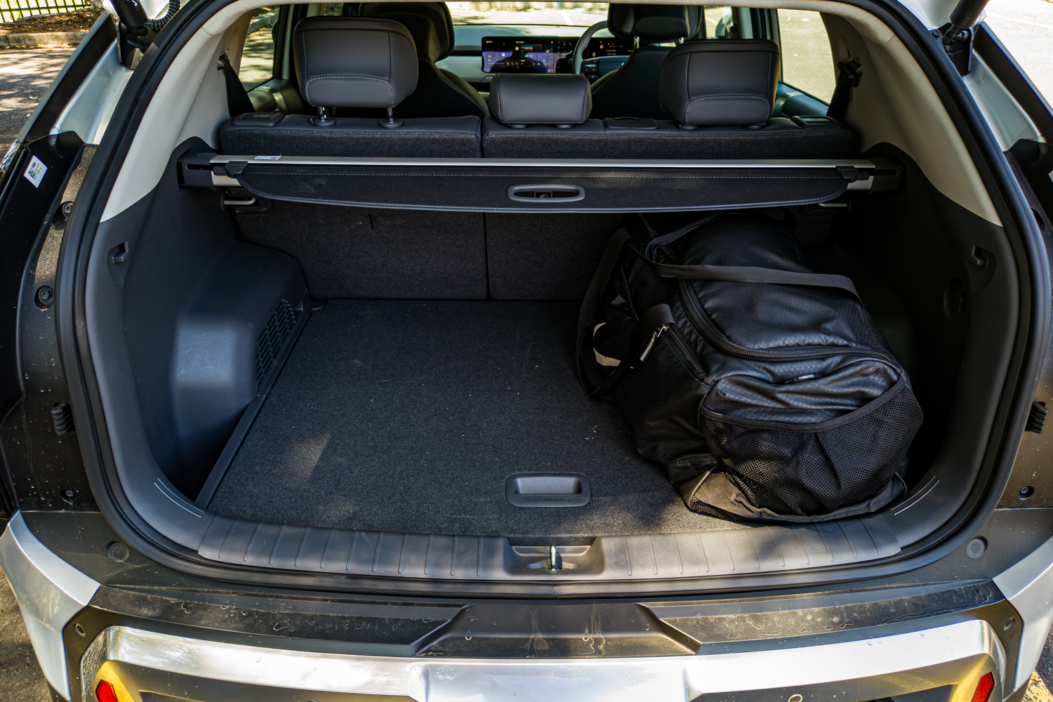 Open boot of the silver 2026 Kia EV3 Earth Long Range with a duffel bag loaded and the rear seats upright
