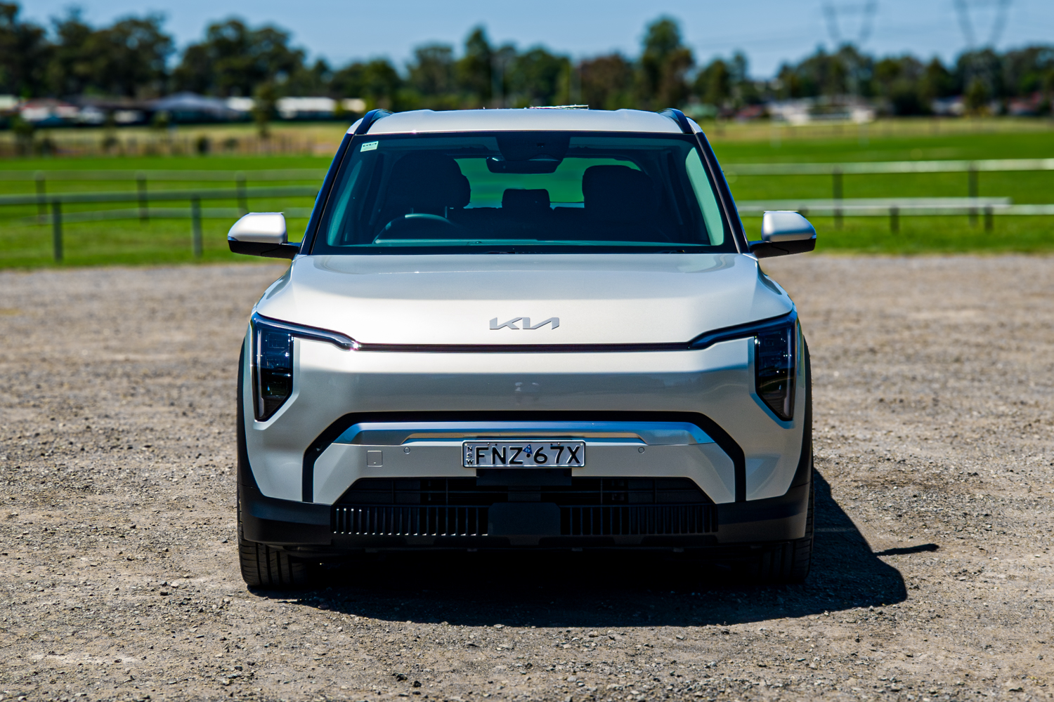 Straight-on front view of the 2026 Kia EV3 Earth Long Range with parkland behind