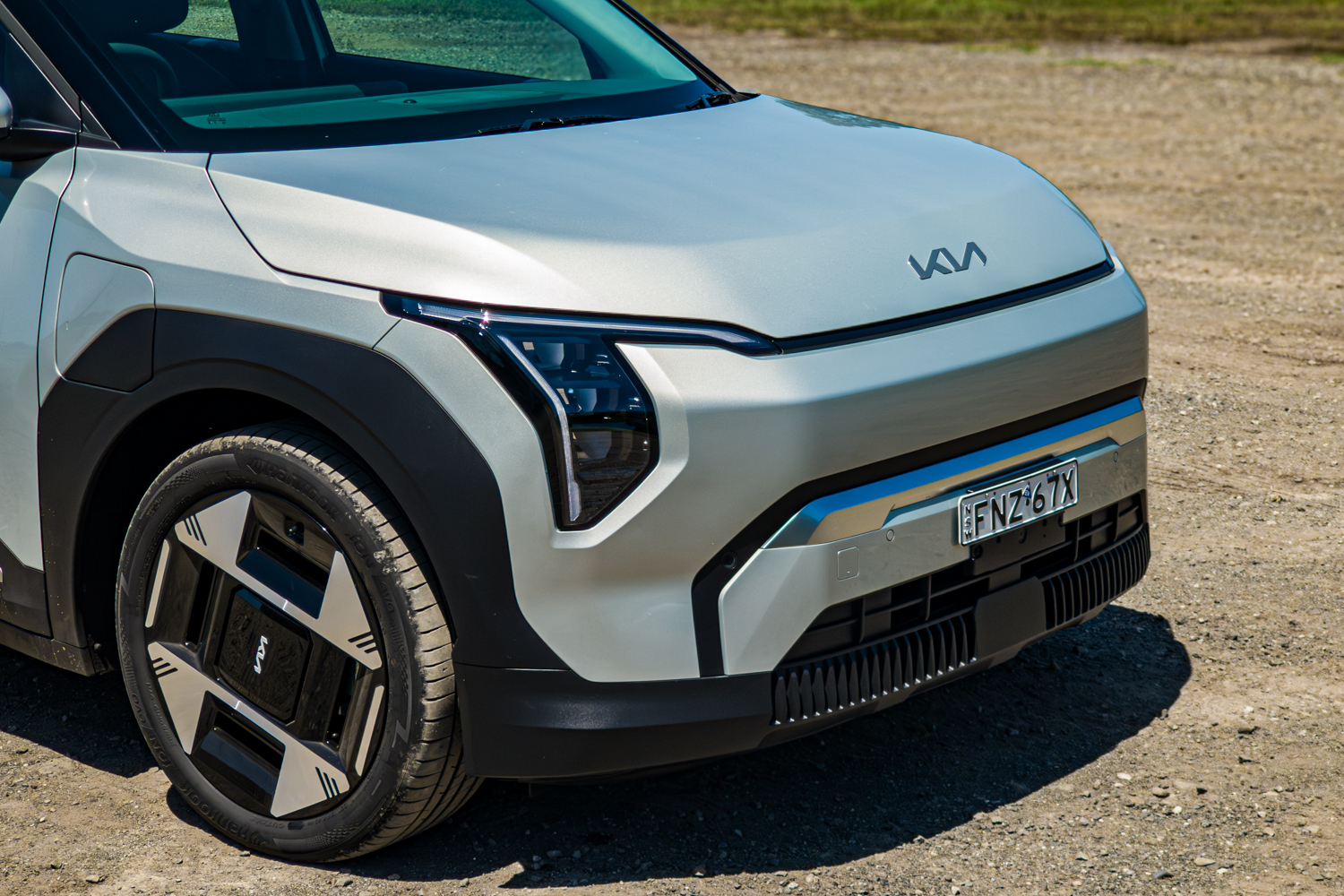 Close front three-quarter view of the silver 2026 Kia EV3 Earth Long Range showing headlight, wheel and badge
