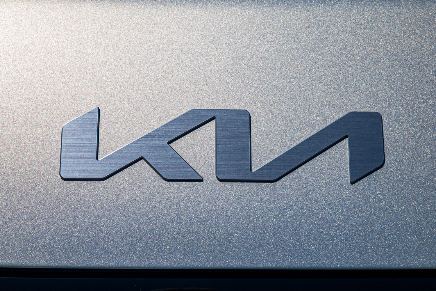 Close-up of the brushed Kia logo badge on the silver 2026 Kia EV3 Earth Long Range
