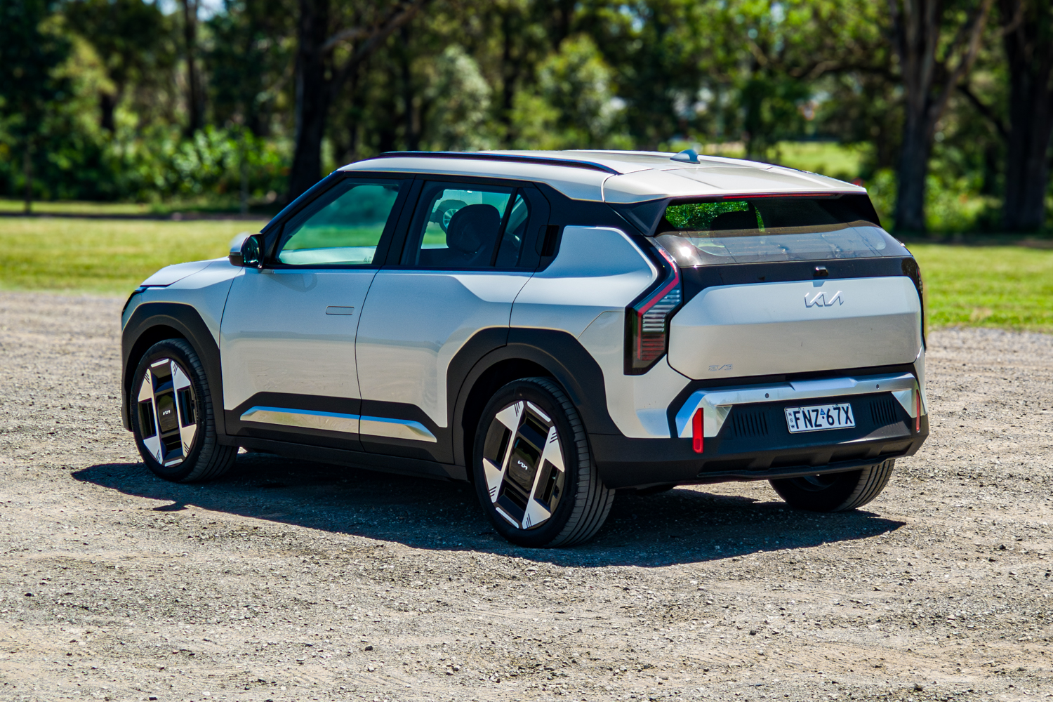 Passenger's-side rear three-quarter of the 2026 Kia EV3 Earth Long Range on gravel