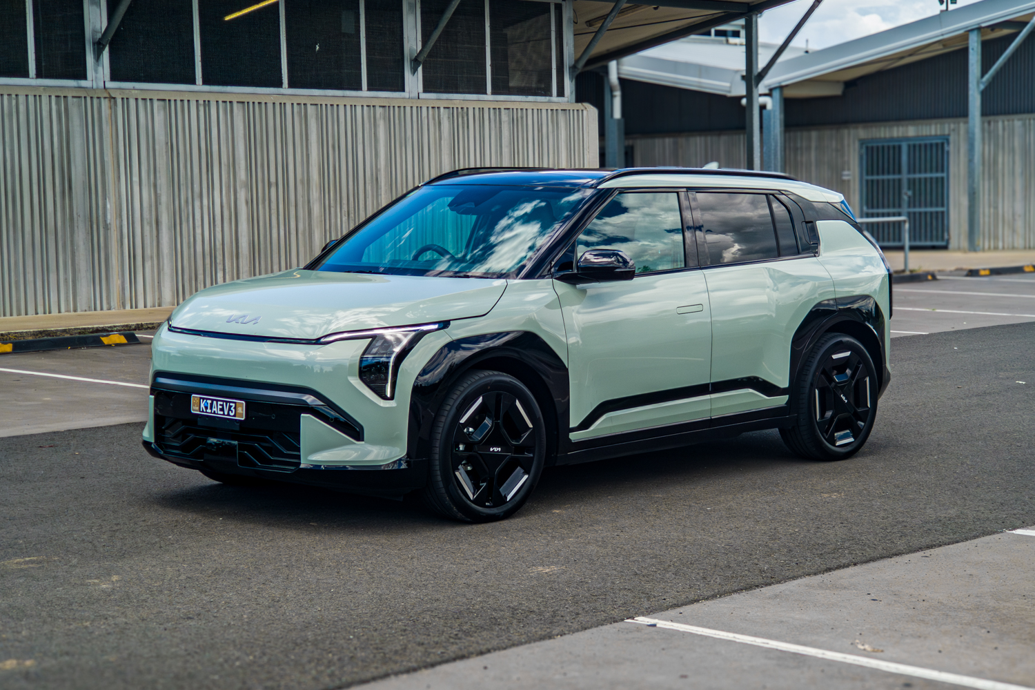 Front left three-quarter view of the 2026 Kia EV3 GT-Line near an industrial building
