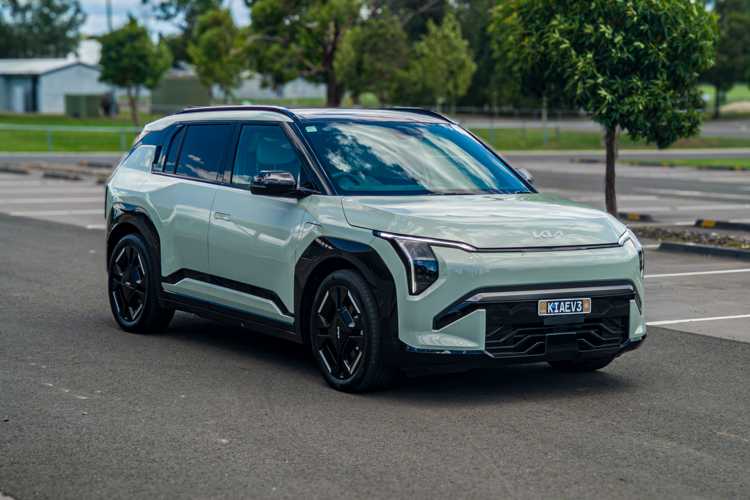 Wide front-left three-quarter view of the 2026 Kia EV3 GT-Line with trees behind