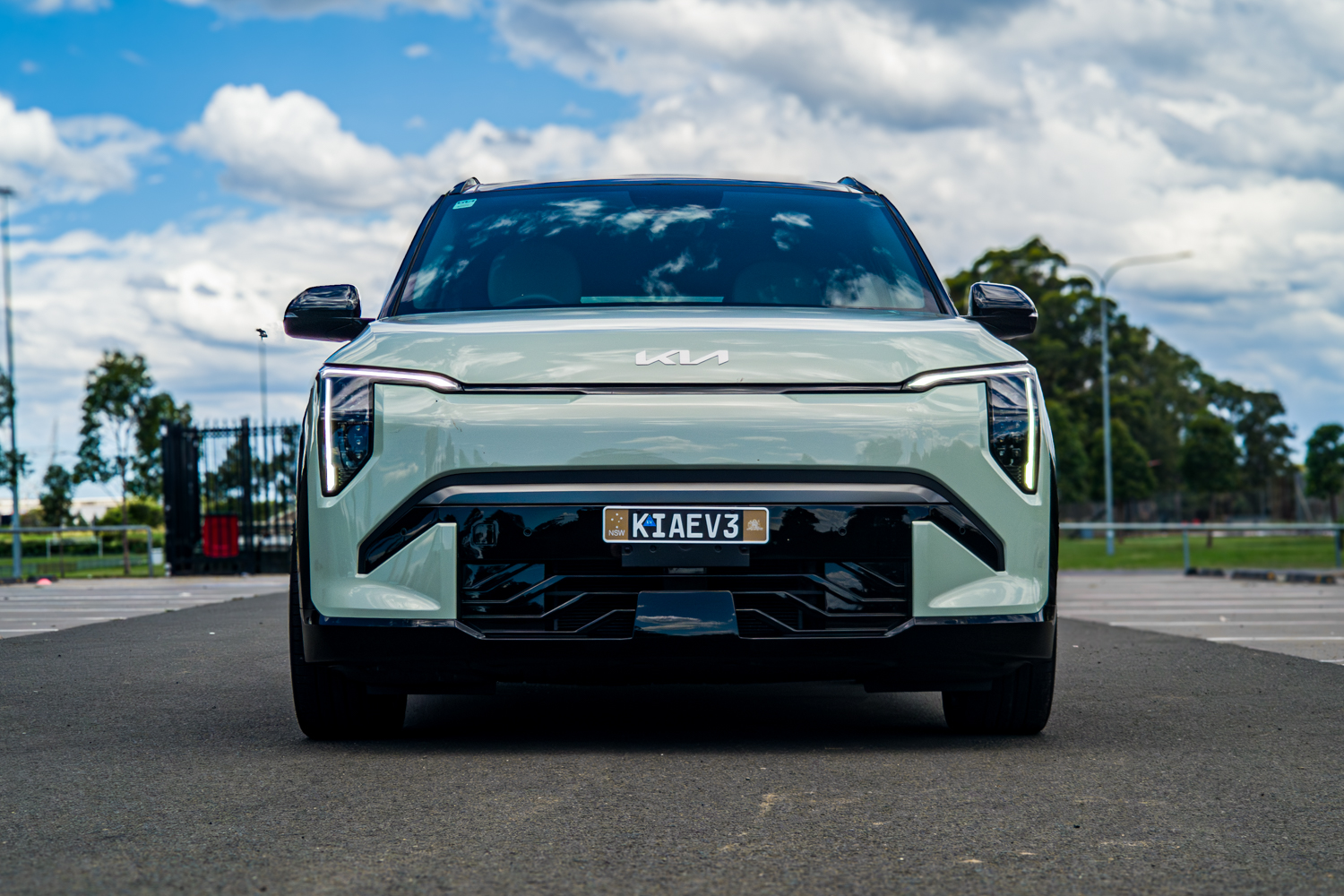 Wide front straight-on view of the 2026 Kia EV3 GT-Line against a cloudy sky