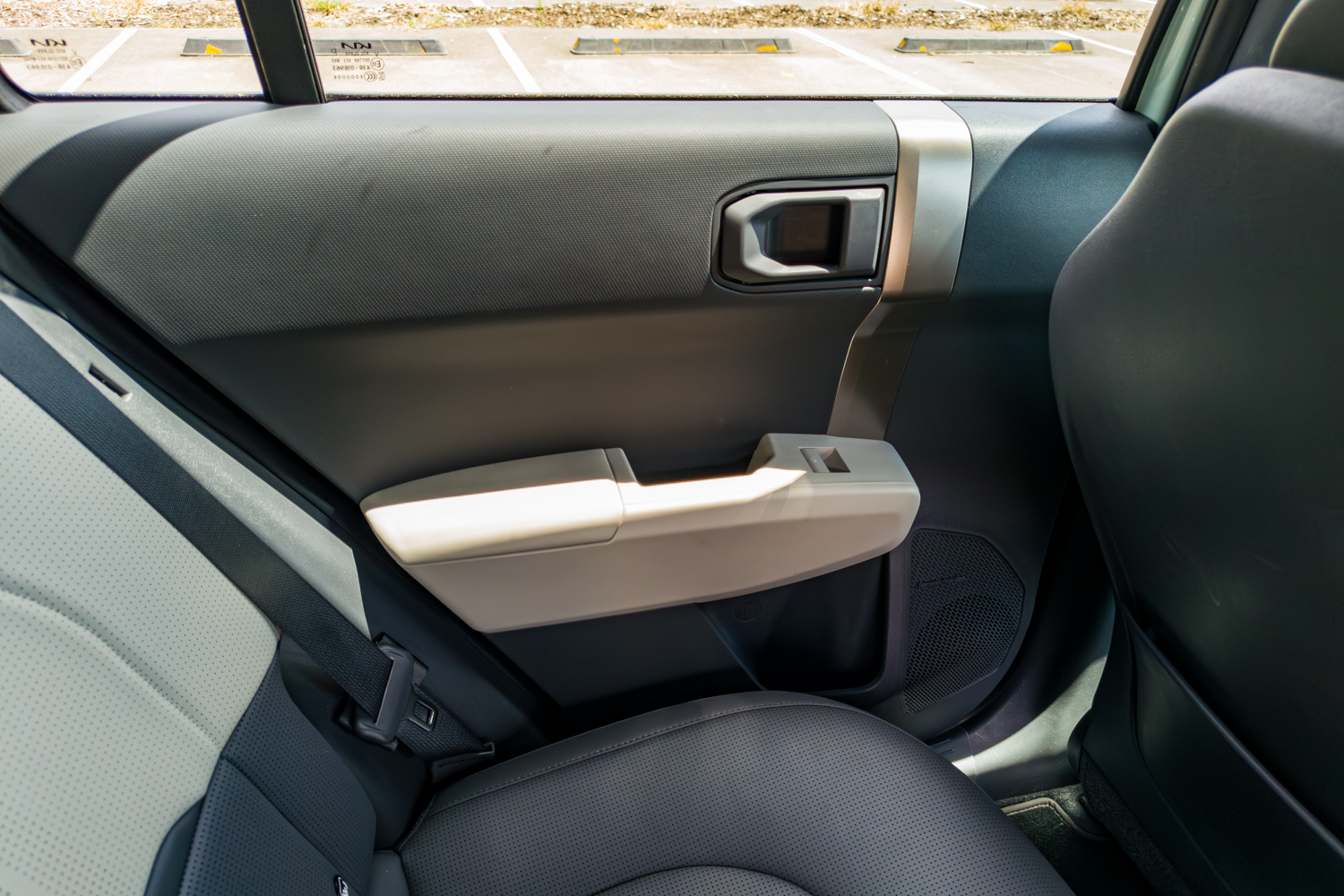 Rear door panel of the 2026 Kia EV3 GT-Line with silver trim insert and speaker