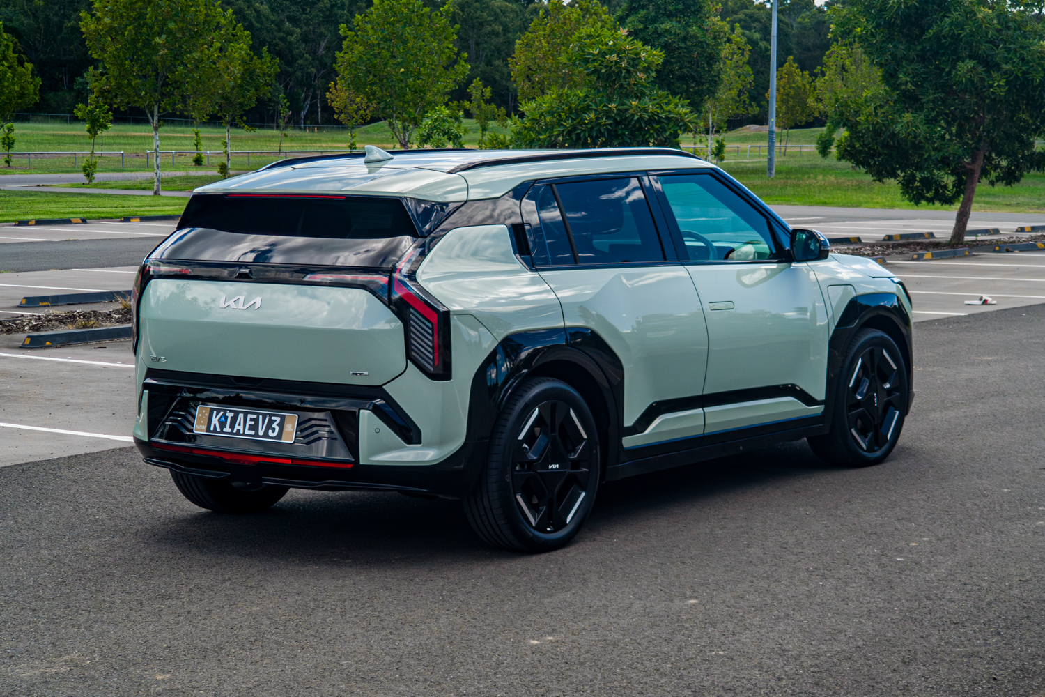 Rear left three-quarter view of the 2026 Kia EV3 GT-Line showing tail lights and spoiler