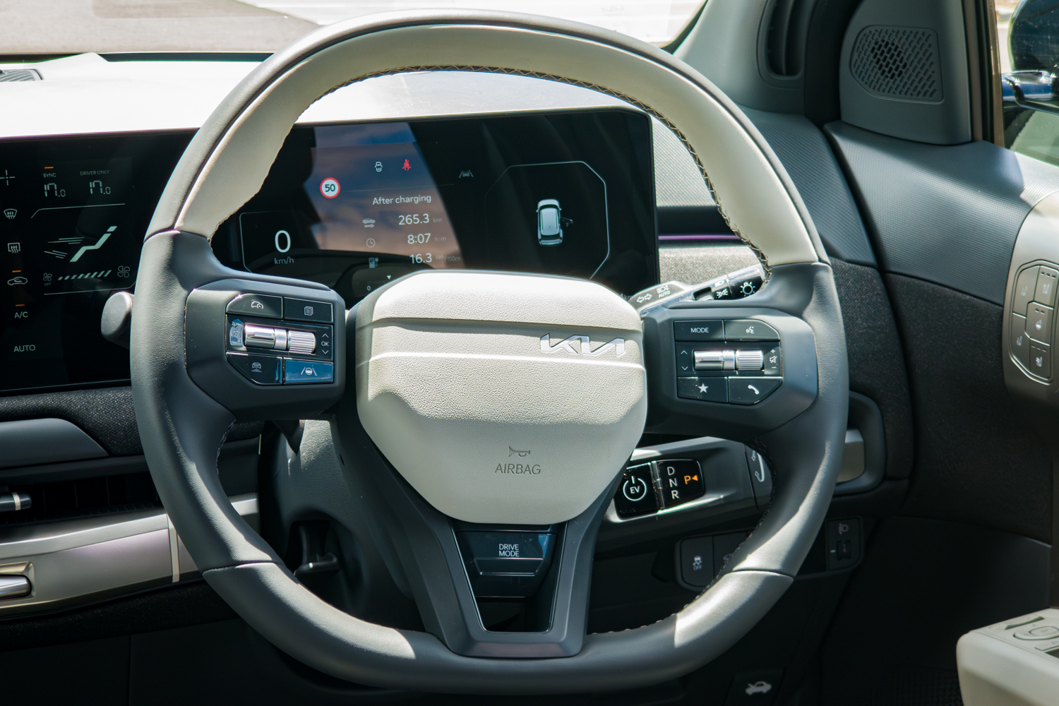 Two-tone cream and dark steering wheel of the 2026 Kia EV3 GT-Line with Kia badge