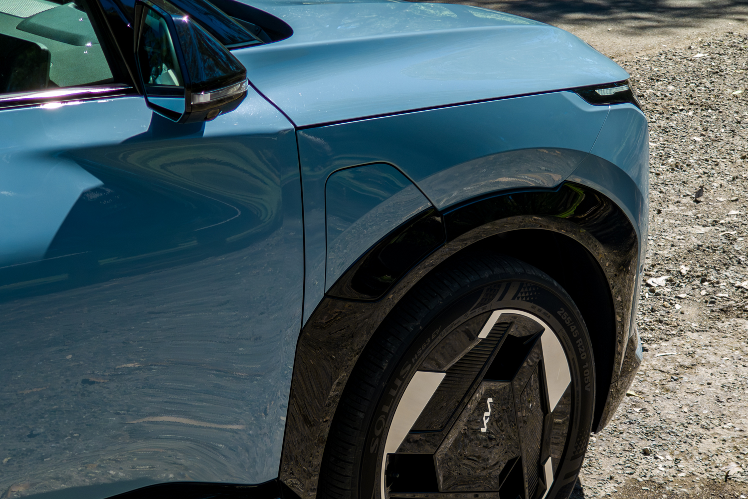 Driver-side front fender of the blue Kia EV5 GT-Line showing the closed charging port flap