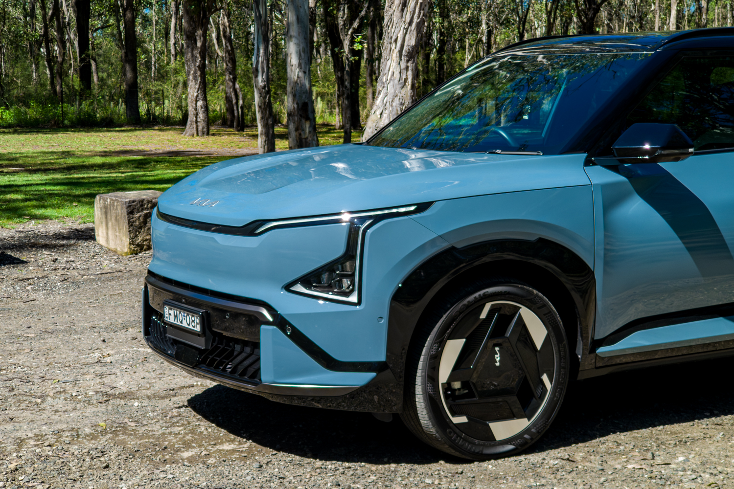 Close front-quarter detail of the blue Kia EV5 GT-Line headlight and 20-inch wheel