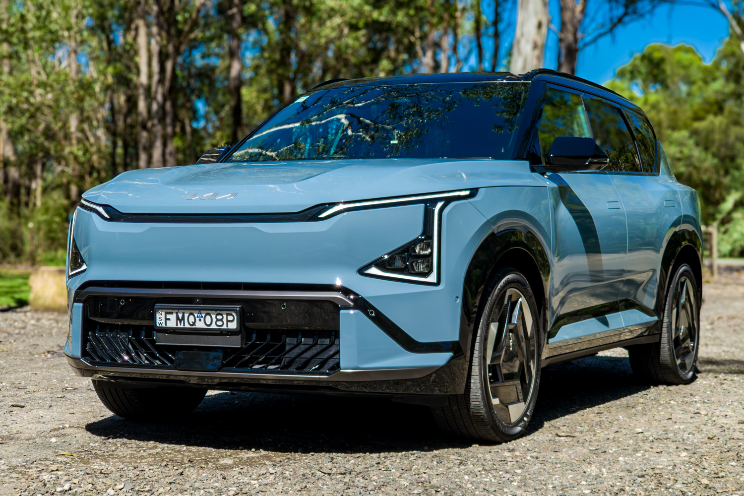 Front three-quarter of the blue Kia EV5 GT-Line electric SUV parked in bushland