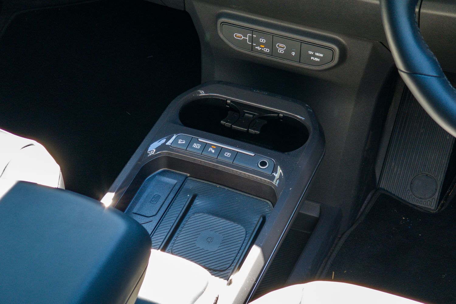 Top-down view of the Kia EV5 GT-Line centre console with wireless charging pad and cupholders