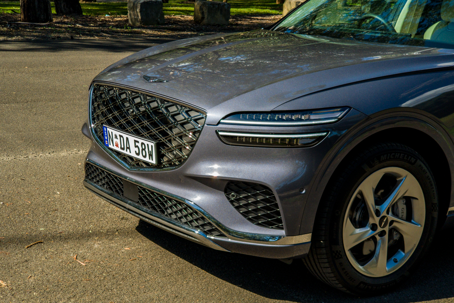 Close-up of the 2026 Genesis GV70 2.5T Advanced passenger-side front corner showing the grille, headlight and 19-inch wheel
