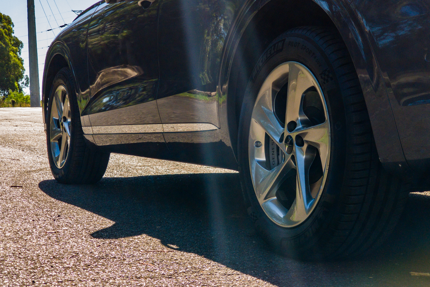 Low ground-level view along the side of the 2026 Genesis GV70 2.5T Advanced showing the chrome sill strip and 19-inch wheels