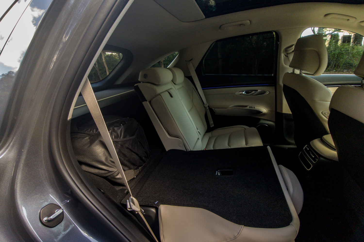 2026 Genesis GV70 2.5T Advanced with one rear seat folded flat showing the 60:40 split and a bag in the boot