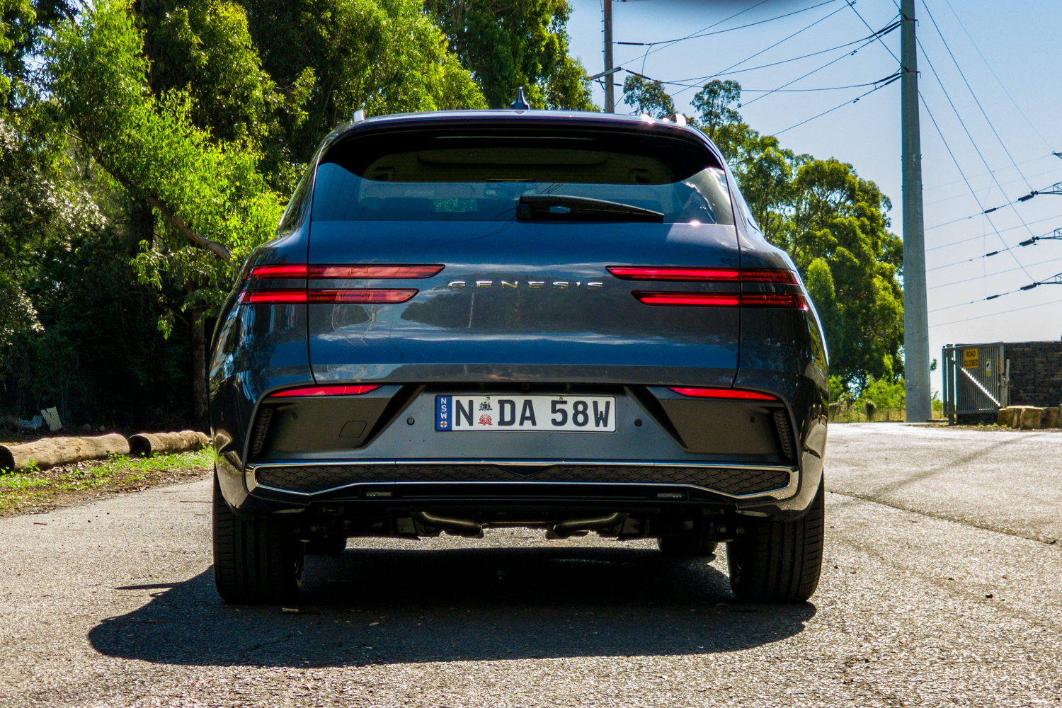 Low straight-on rear view of the 2026 Genesis GV70 2.5T Advanced with the tail lights lit