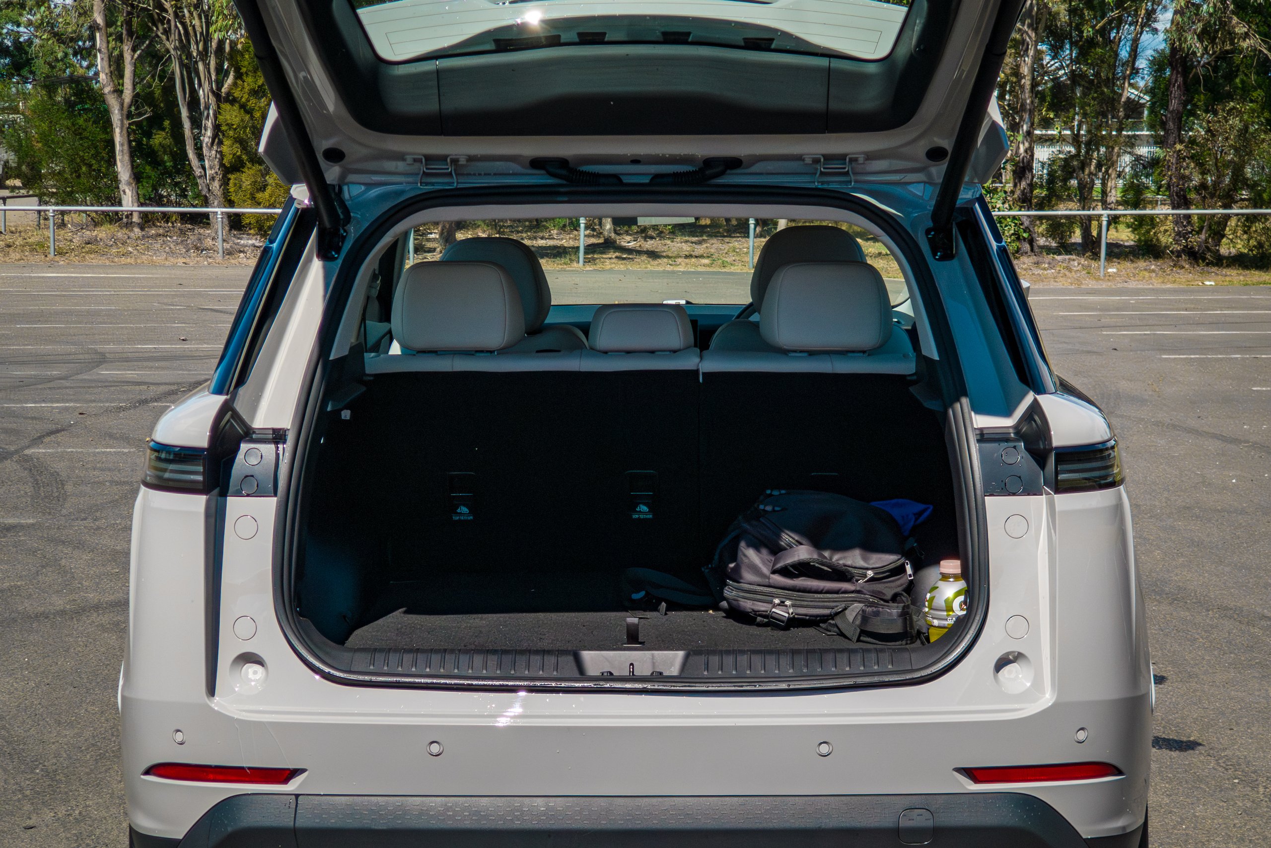 Open tailgate of the Stone Grey 2026 Jaecoo J5 EV Summit showing the boot with a backpack and rear seats upright