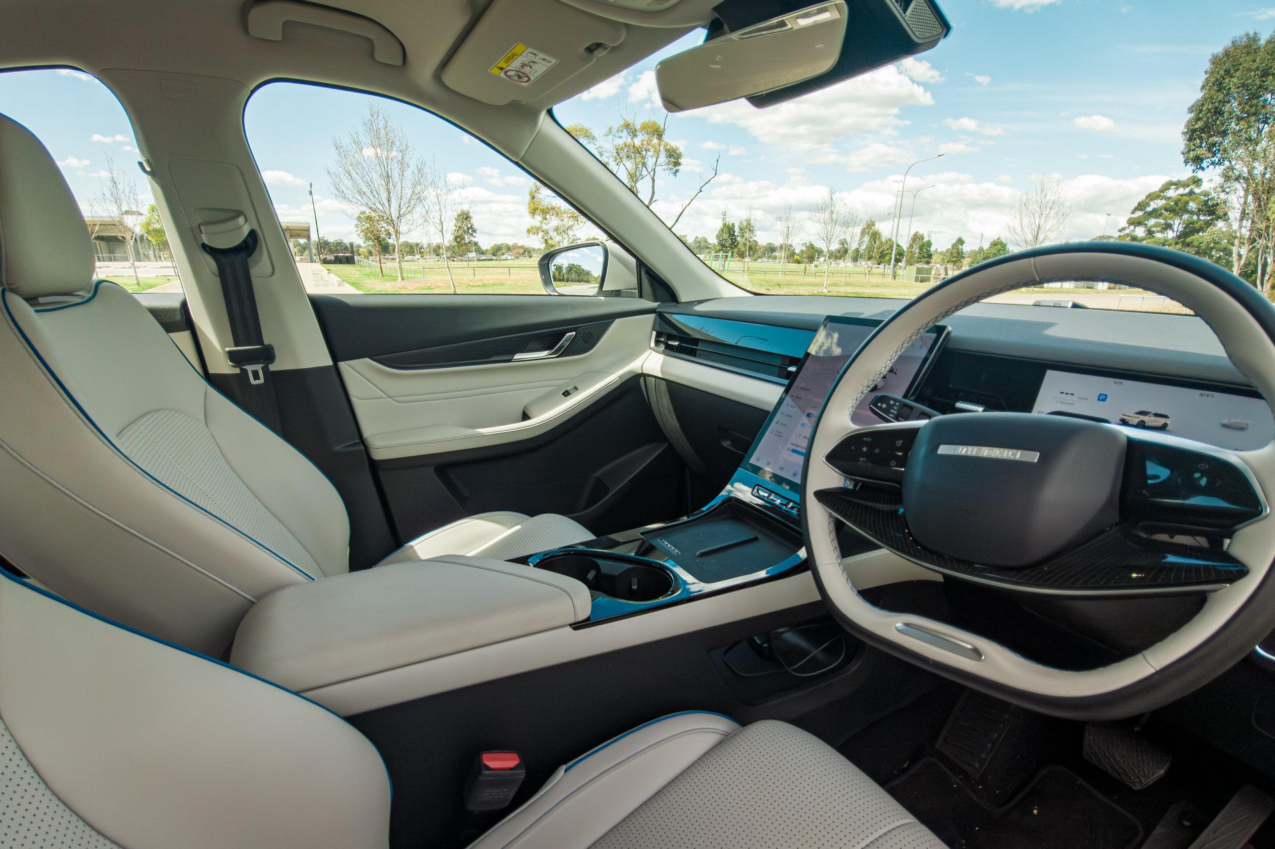 Front seats and dashboard of the 2026 Jaecoo J5 EV Summit viewed from the passenger door with blue piping and centre screen