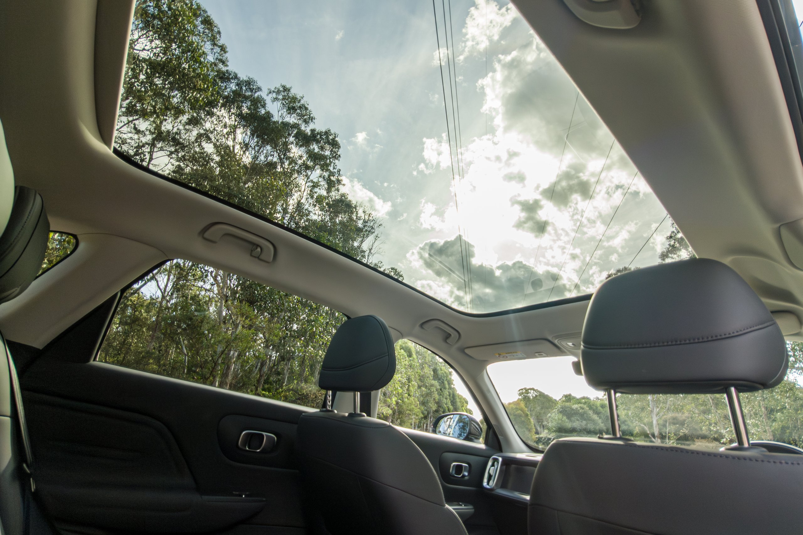 View up through the 2026 Leapmotor B10 expansive panoramic glass sunroof showing blue sky and trees
