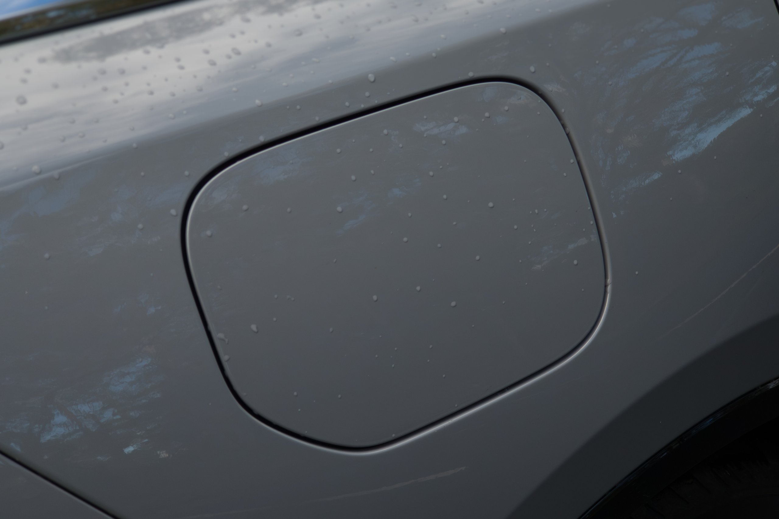 Closed charge flap on the light grey rear quarter panel of the 2026 Mazda 6e GT