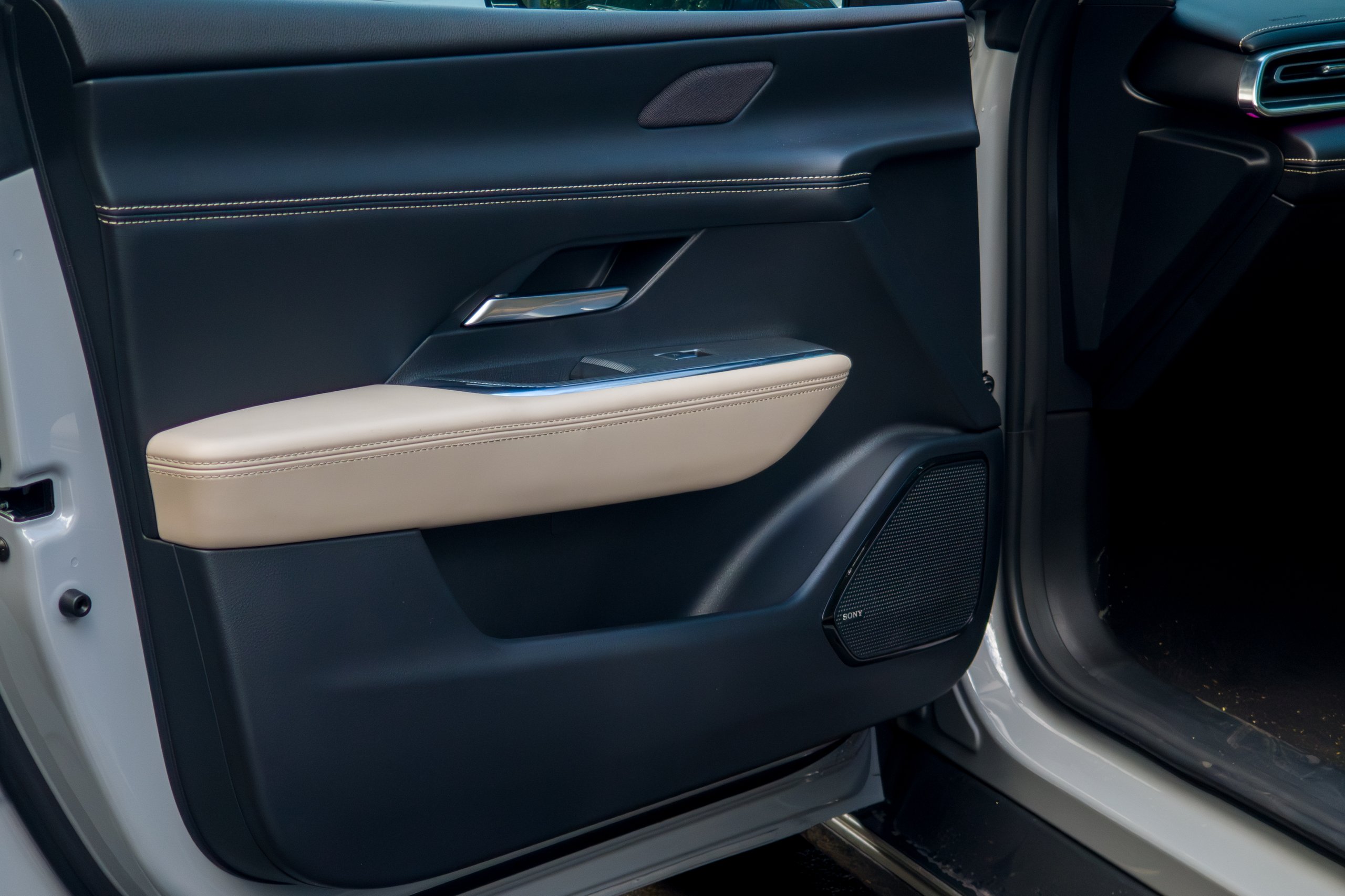Front door trim of the 2026 Mazda 6e GT with beige armrest and Sony speaker grille