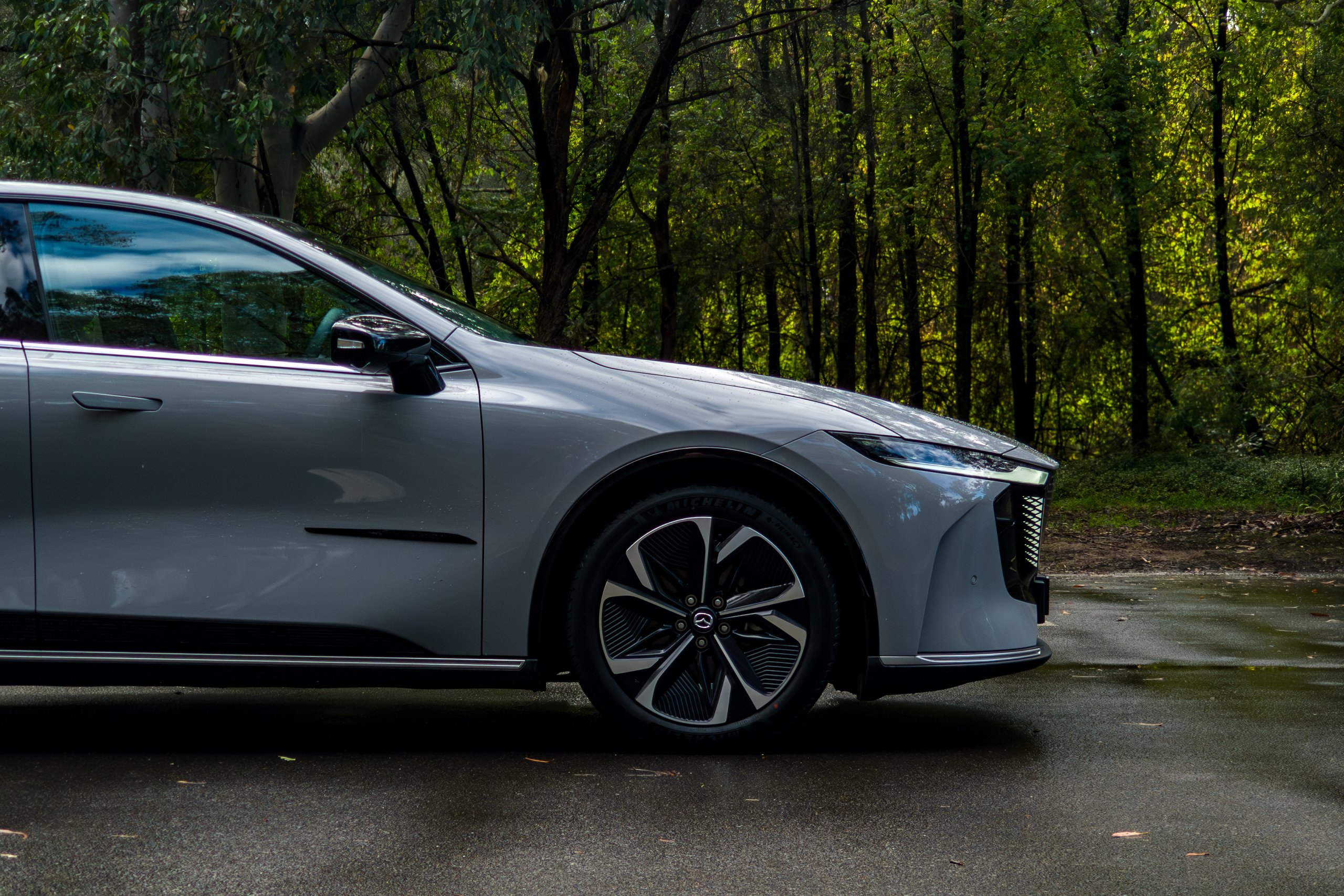 Front driver-side view of the 2026 Mazda 6e GT showing wheel arch, alloy wheel and mirror