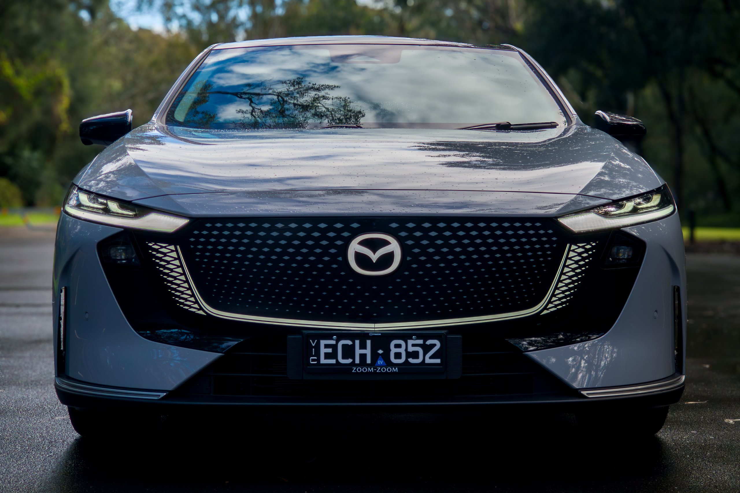 Straight-on front view of the light grey 2026 Mazda 6e GT showing grille panel and LED headlights