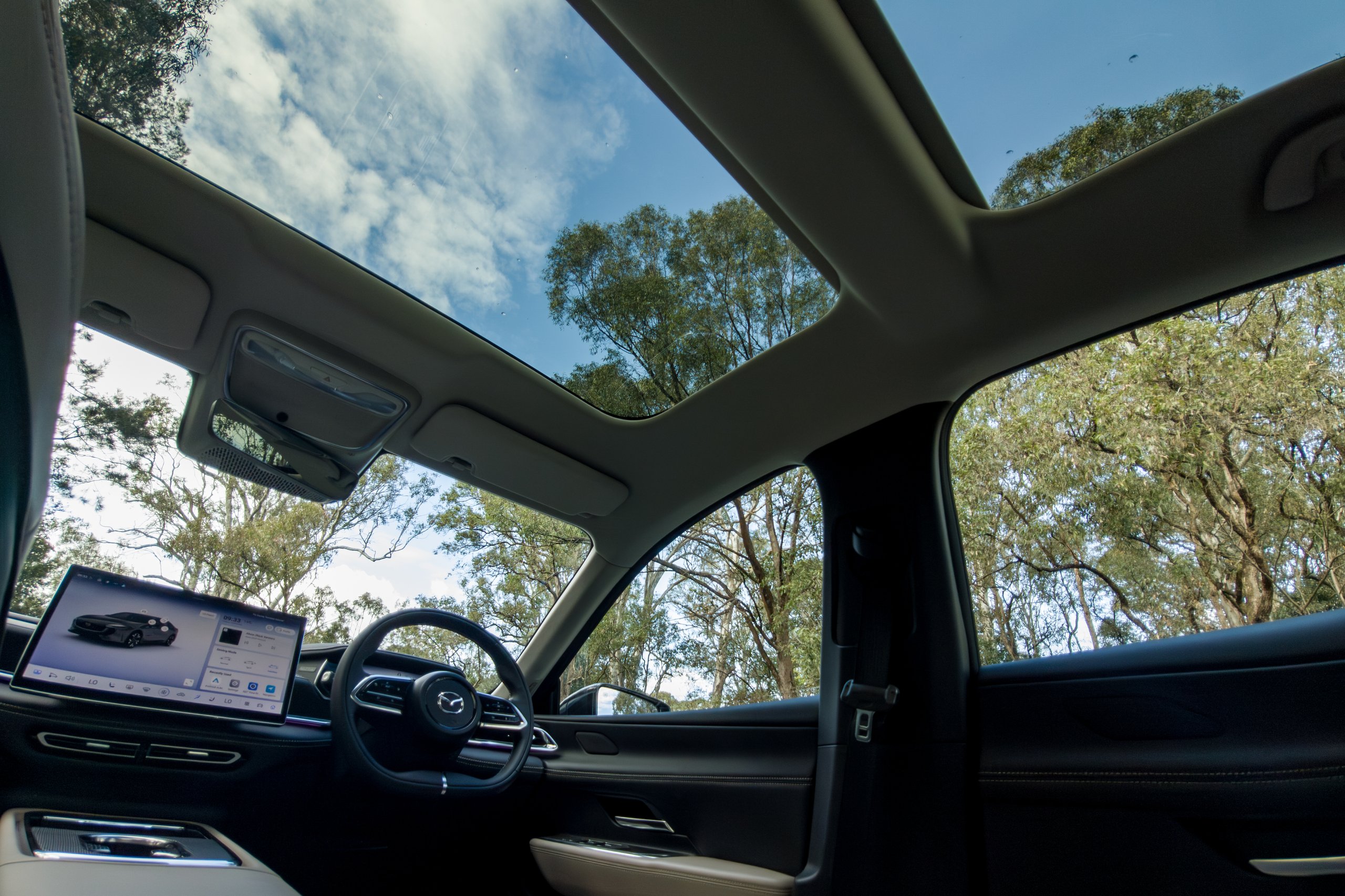 Panoramic glass roof of the 2026 Mazda 6e GT seen from inside with gum trees overhead