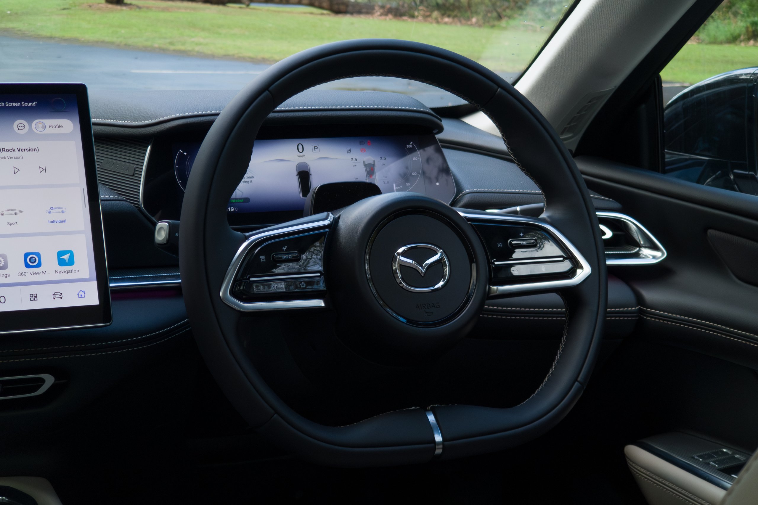 Steering wheel controls and instrument cluster of the 2026 Mazda 6e GT from the driver seat