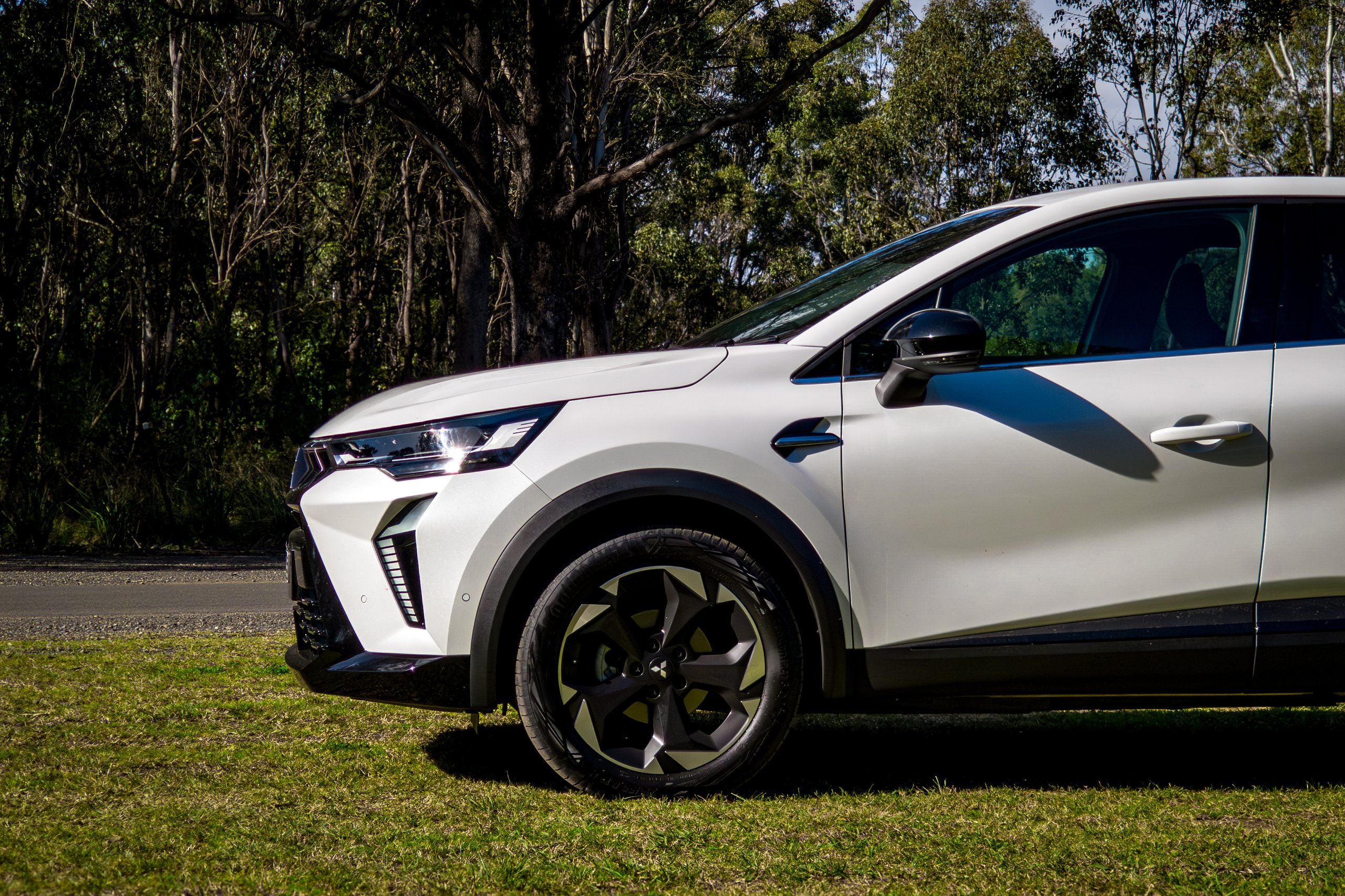 Front wheel and headlight detail of the Crystal White 2026 Mitsubishi ASX Aspire on grass