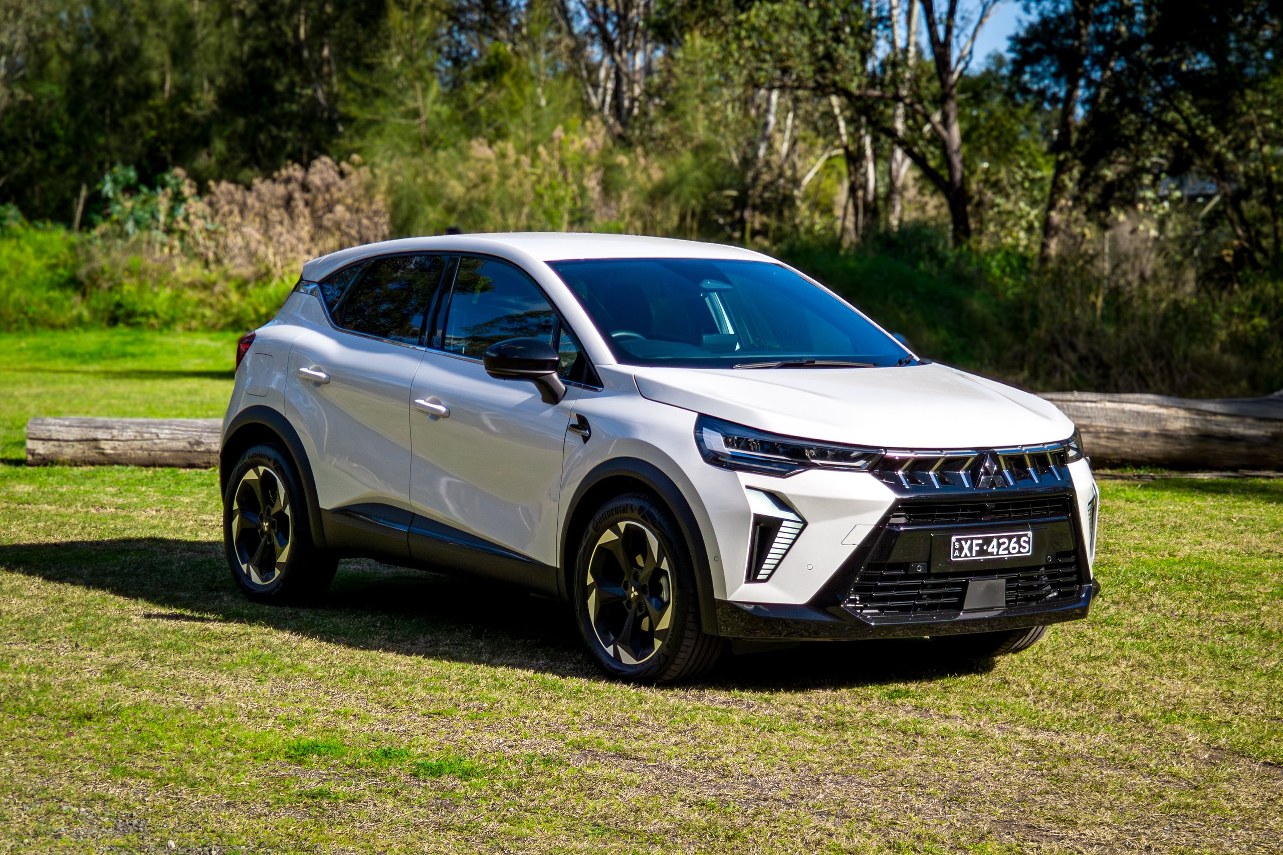 Crystal White 2026 Mitsubishi ASX Aspire front three-quarter from the driver's side with logs behind