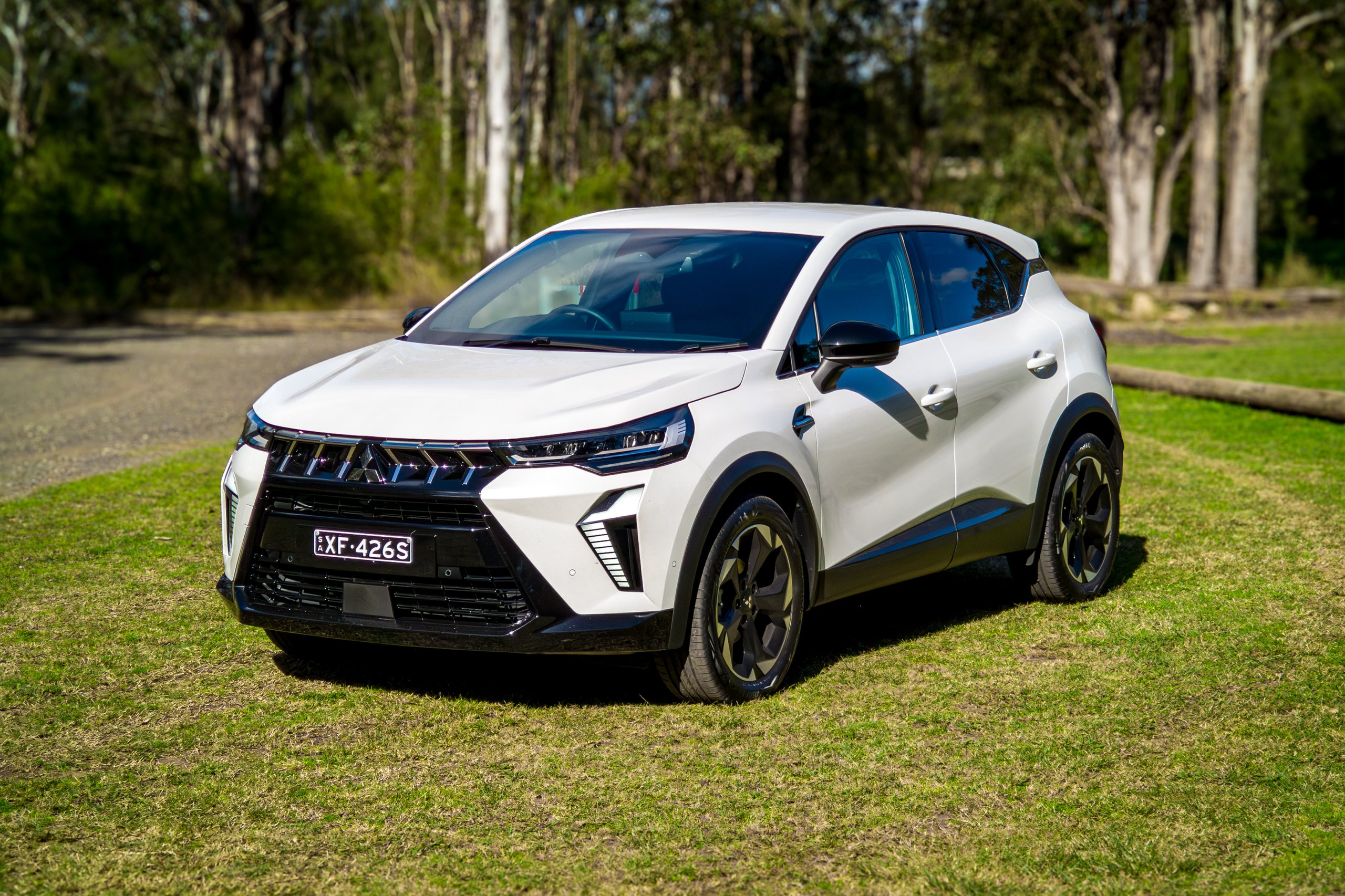 Crystal White 2026 Mitsubishi ASX Aspire front three-quarter view with gravel and bushland behind