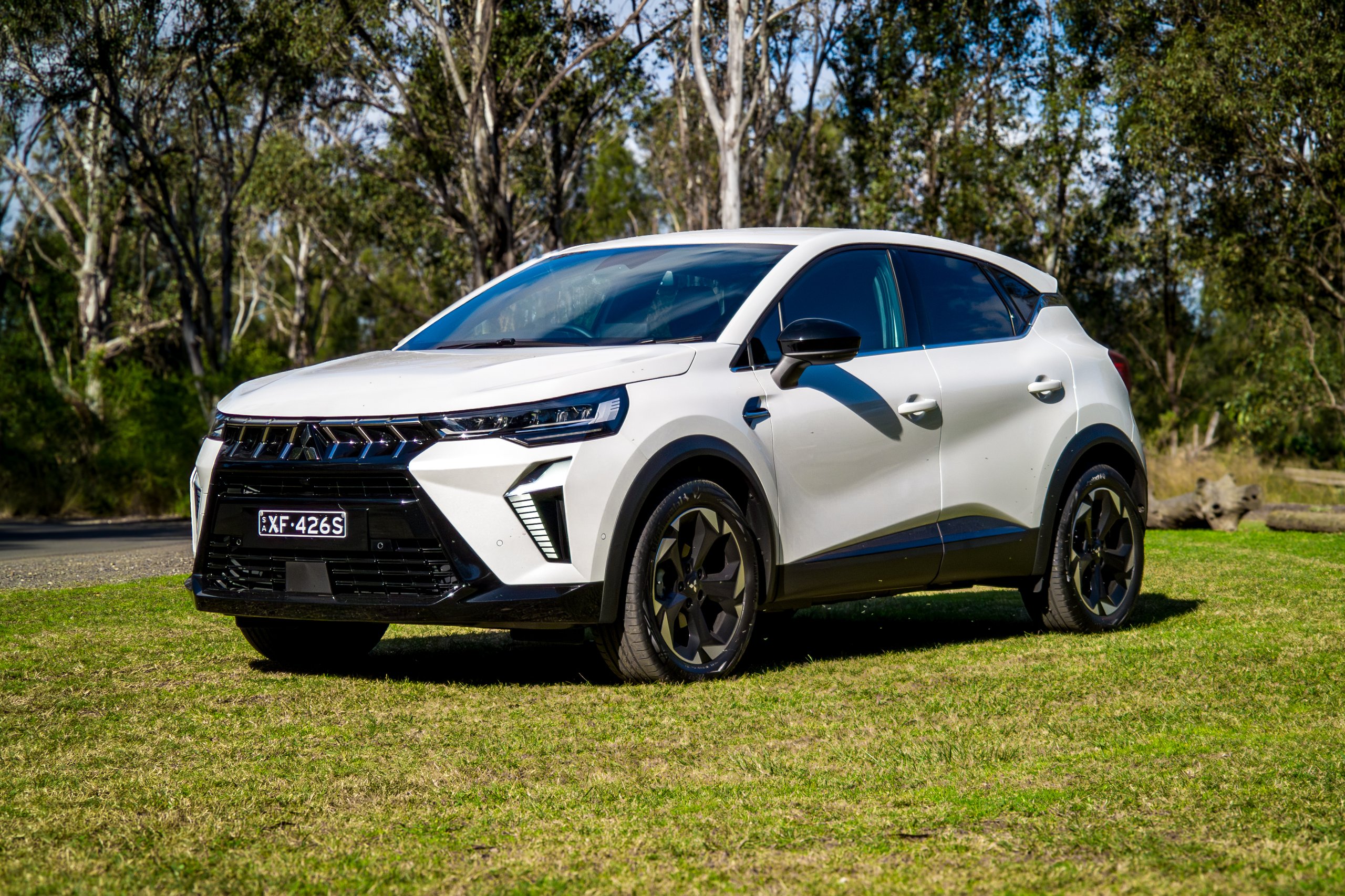 Crystal White 2026 Mitsubishi ASX Aspire front three-quarter parked on grass beside a gravel track