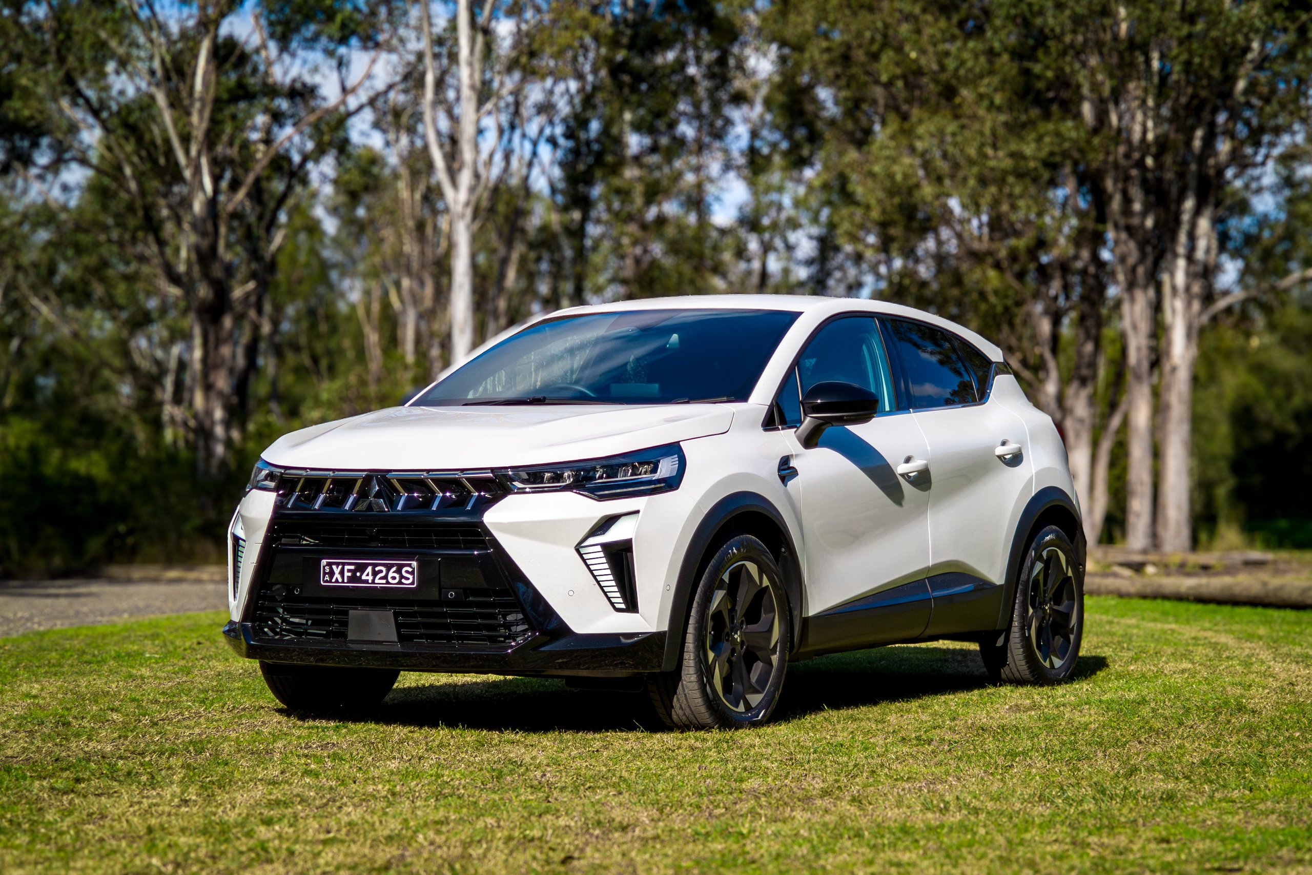 Crystal White 2026 Mitsubishi ASX Aspire front three-quarter view from the passenger side on grass